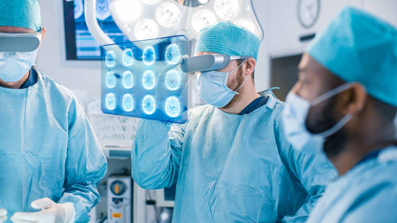Three surgeons looking at brain scans through virtual reality goggles.