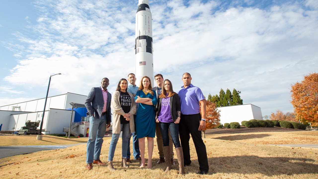 Group of people standing in front of a rocket