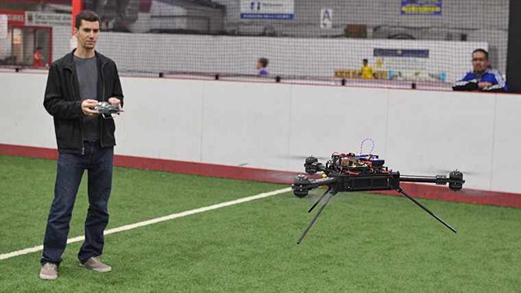 Man inside an arena flying a drone.