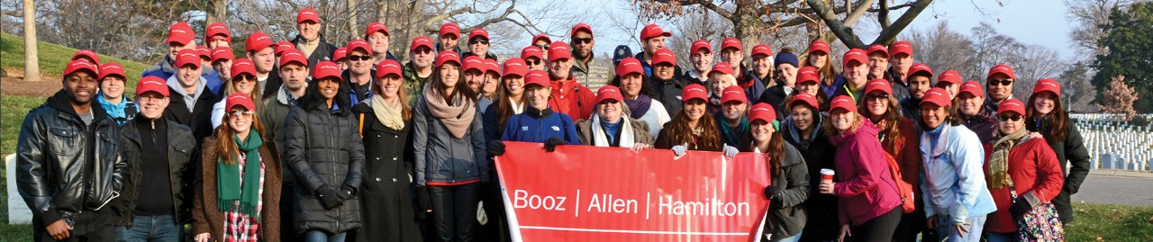 Group of volunteers for the Brains and Hearts Campaign standing outside holding a Booz Allen Hamilton banner.