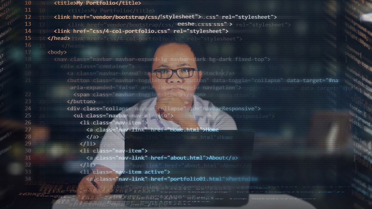 Person sitting at desk looking forward at code on a screen.