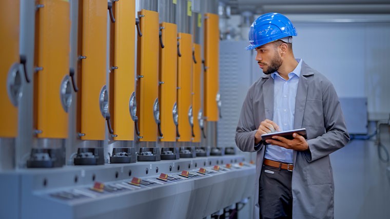 man in hardhat with tablet overseeing factory operations