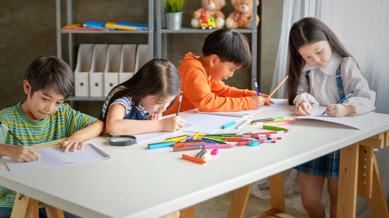 Group of children drawing and coloring at a table together