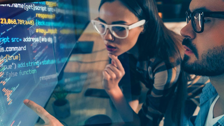 man and woman assessing code on a lager monitor