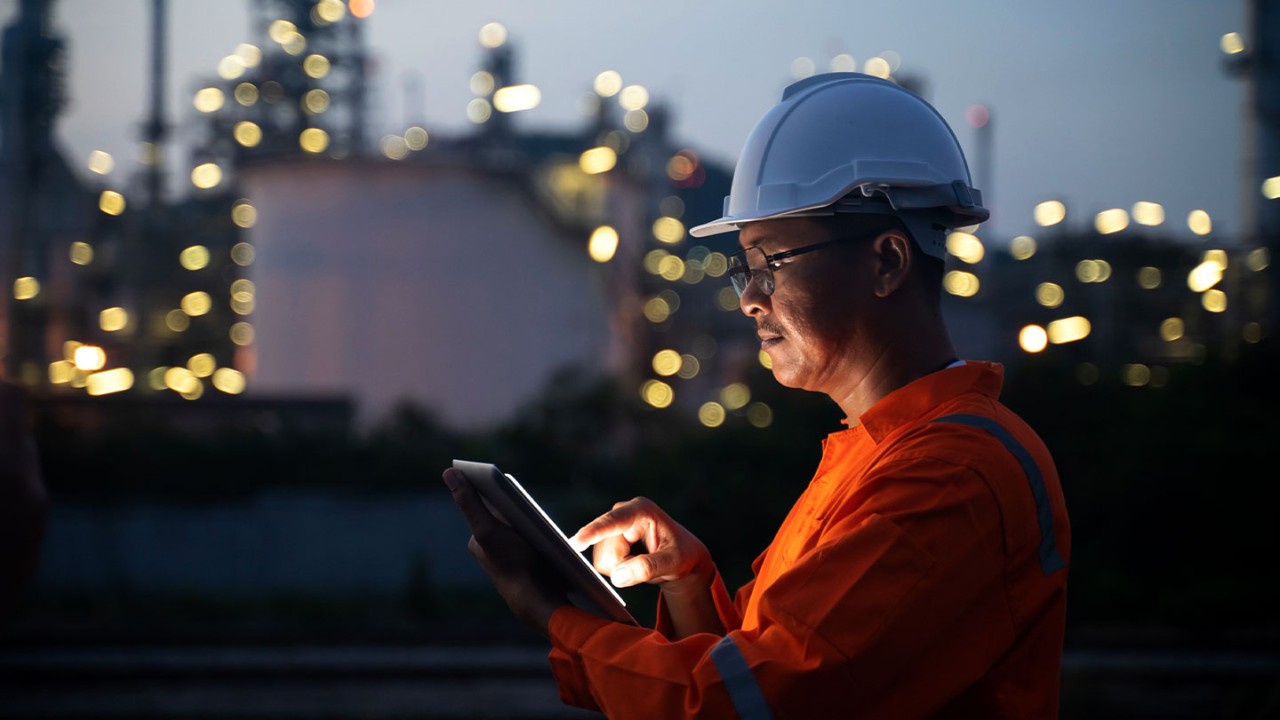 Engineer on a tablet at night working at an oil refinery